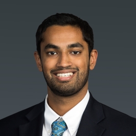 Dr. Munjunathan headshot, smiling in suit, with gray background